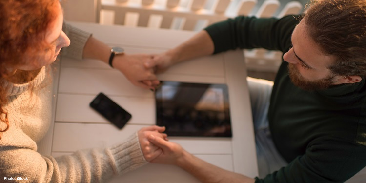 High angle view of a couple sitting at a table praying together.