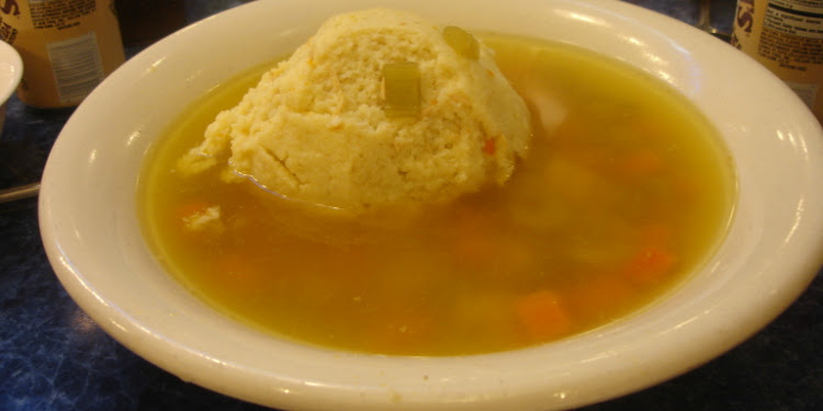 Matzah ball soup in a white bowl.