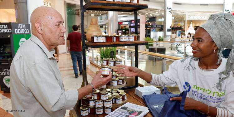 IFCJ staff passing out jars of honey to people in the mall.