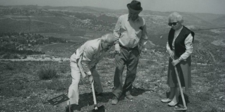 Black and white image of three elderly people playing a game outside.