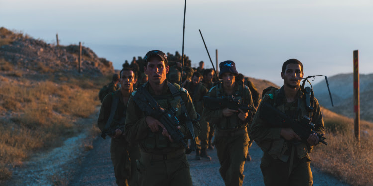 Several soldiers marching through a road in the hill.