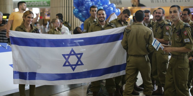 Group of IDF soldiers holding the Israeli flag.