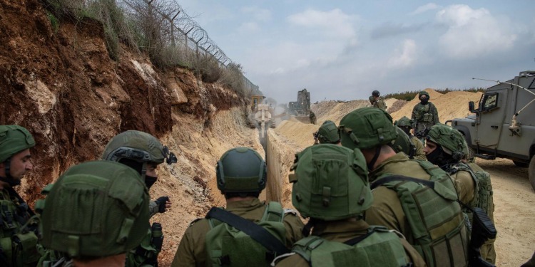 IDF soldiers going up a sandy hill with tanks.