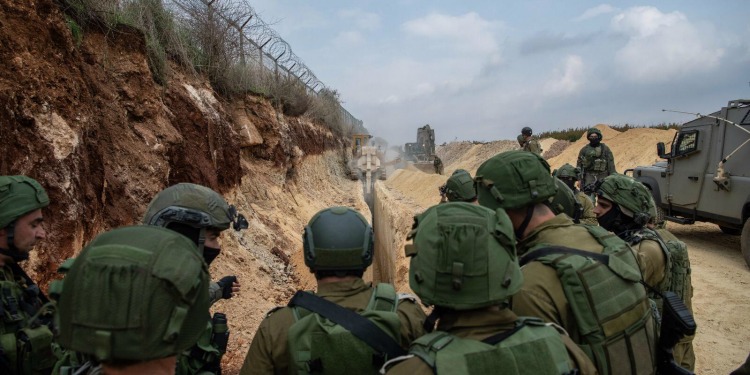 IDF soldiers going up a sandy hill with tanks.