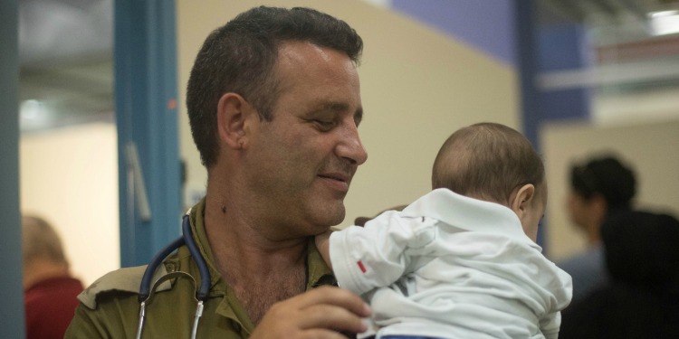 IDF doctor smiling down at a baby.