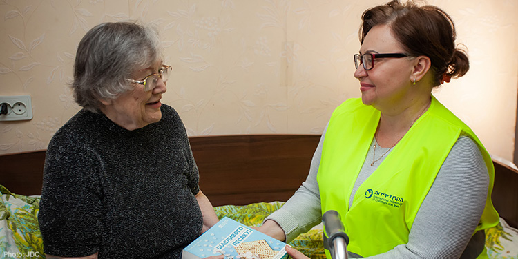 IFCJ Staff giving box of matzah to elderly woman