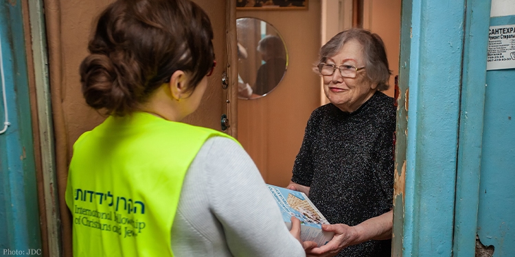 IFCJ staff giving box of matzah to elderly woman