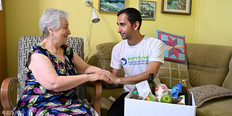 IFCJ Staff member holding an elderly woman's hand