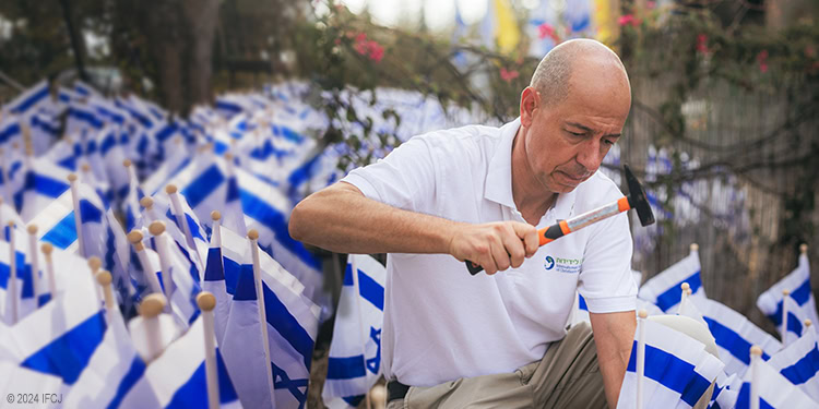 IFCJ employee placing field of flags of Israel in the ground