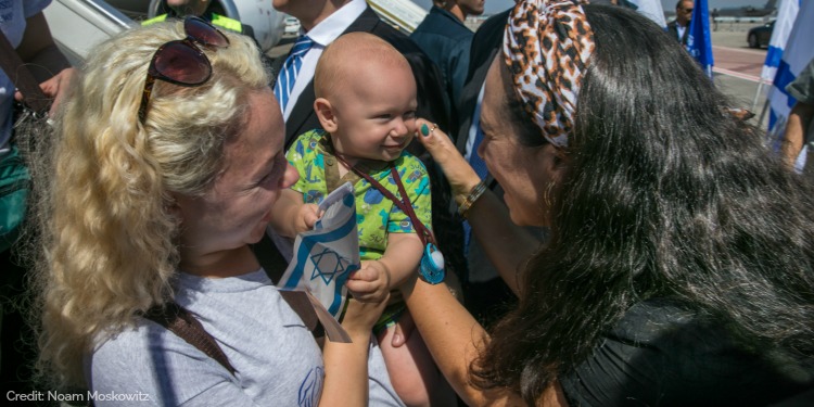 Yael greeting new olim stepping off of airplane, baby, Israeli flag