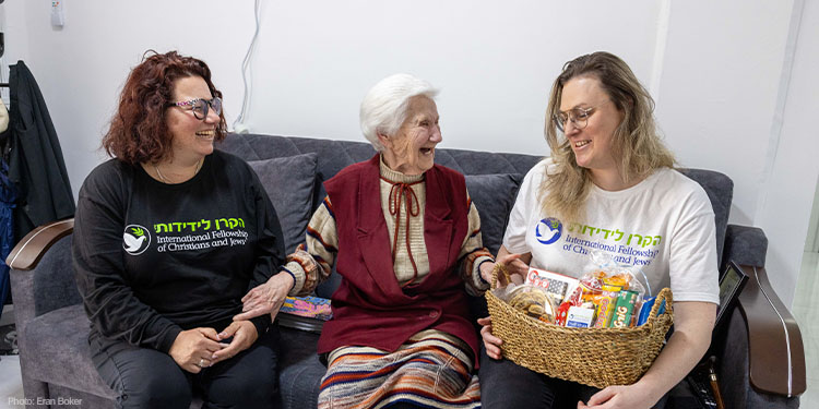 IFCJ staff sitting with elderly woman smiling