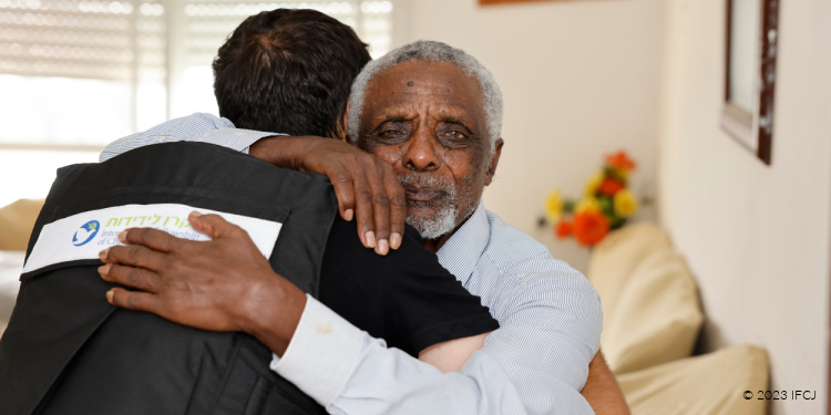 IFCJ volunteer in a flak jacket hugging a recipient.