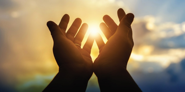 Prayer hands lifted up to the sky