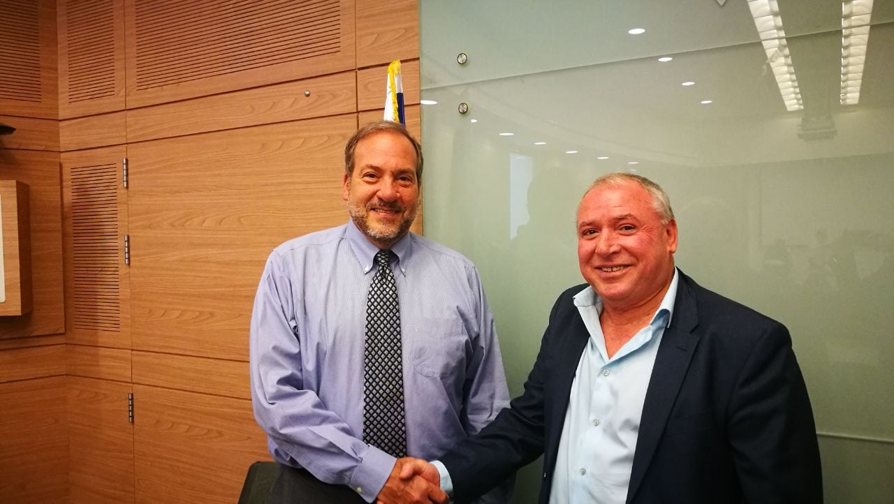 Rabbi Eckstein shaking the hand of another gentlemen, while they both smile.