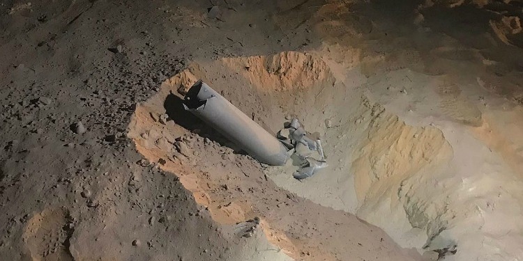 A gray rocket buried in the sand.