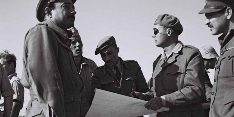 Black and white image of five soldiers going over a piece of paper.