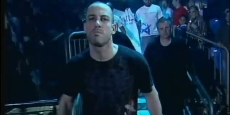 A man in a black t-shirt walking through a crowd in an arena.