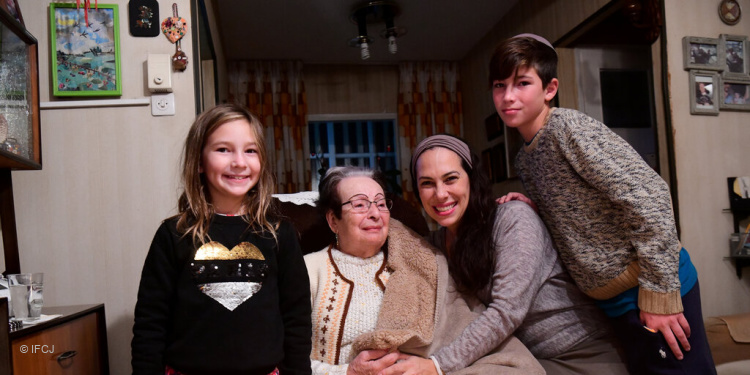 Yael Eckstein teaches her children the joy of giving to others with an elderly woman in Israel