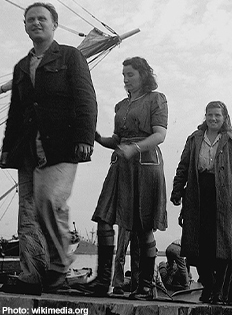 Black and white image of three people walking in a line.