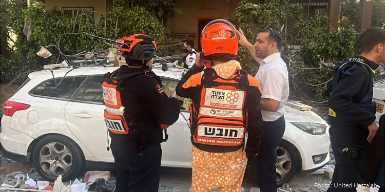 Emergency responders in uniforms and helmets helping a man after a car crash.