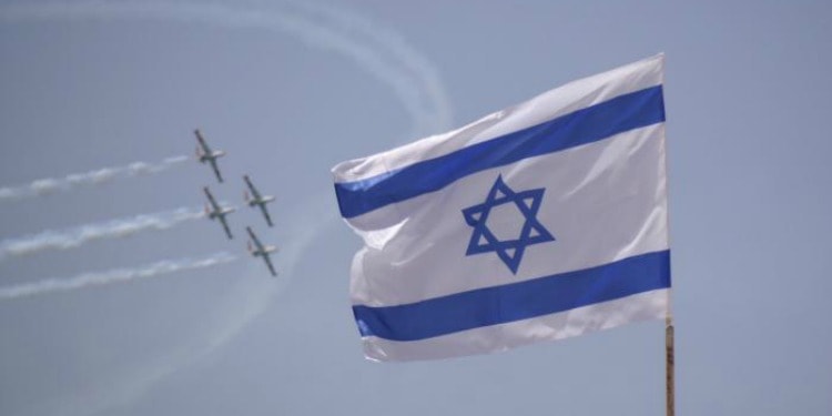 Four jets flying overhead while an Israeli flag is waving in the air during Israel Independence Day.
