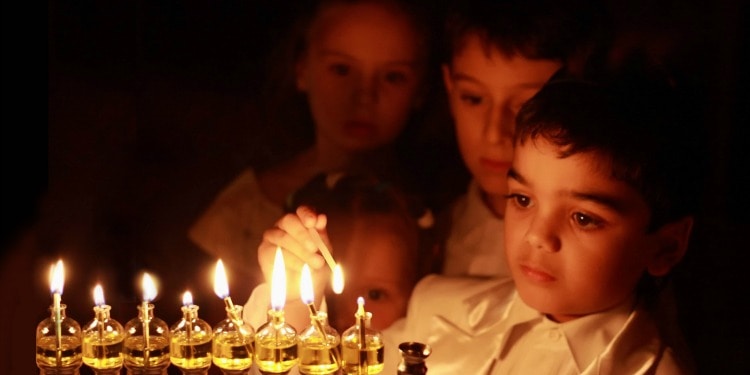 Little boy lighting candles on the menorah for Hanukkah.