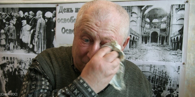 Man using a handkerchief to dry his eyes.