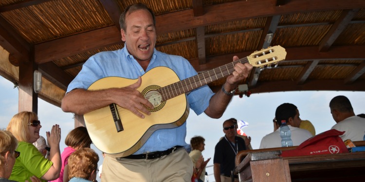 Rabbi Eckstein playing the guitar in a pavilion filled with a large group of pool.
