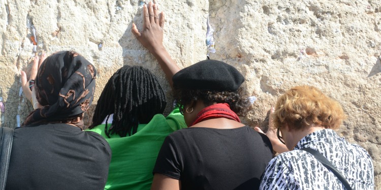 The back of four women facing the Western Wall.