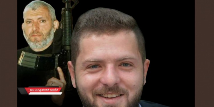 A man smiling with another man holding a weapon behind him.