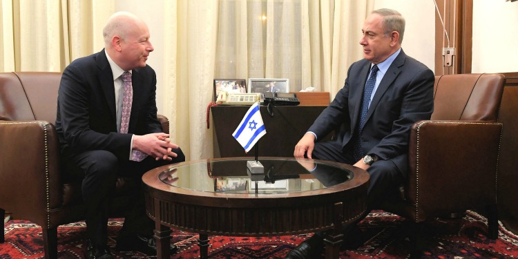 Jason Greenblatt and Bibi talking together over a table with an Israeli flag on it.