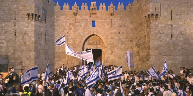 Several people celebrating while waving Israeli flags in the air.