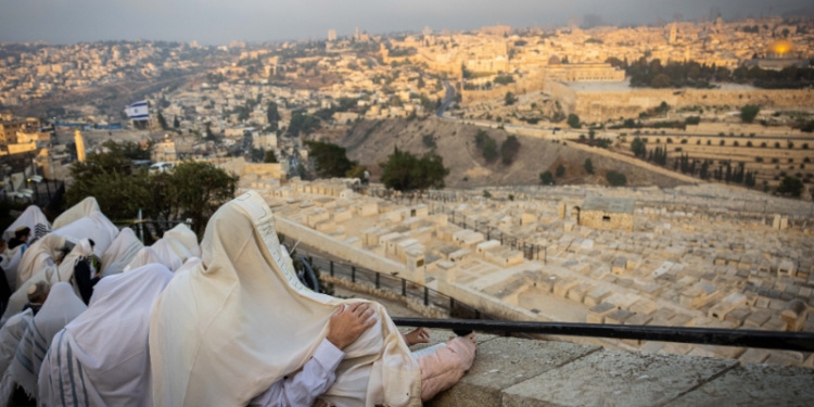 Jewish men covered in white prayer shawls overlooking Jerusalem.