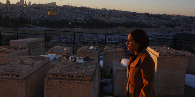 Yael looking into the sunset while a snowy Jerusalem is behind her.