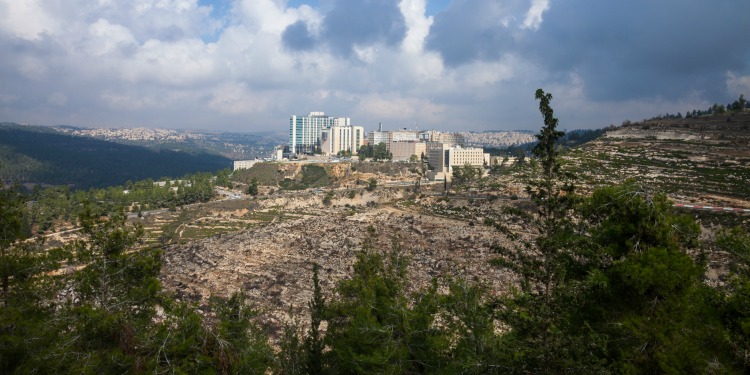 Aerial view of a city with greenery and hills around it.