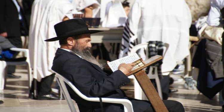 A man reading scripture at a solo desk in public.