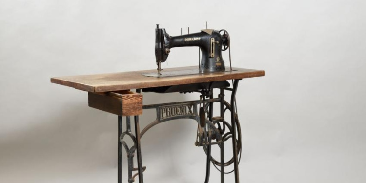 An old Julius Madritsch sewing machine up against a white wall.