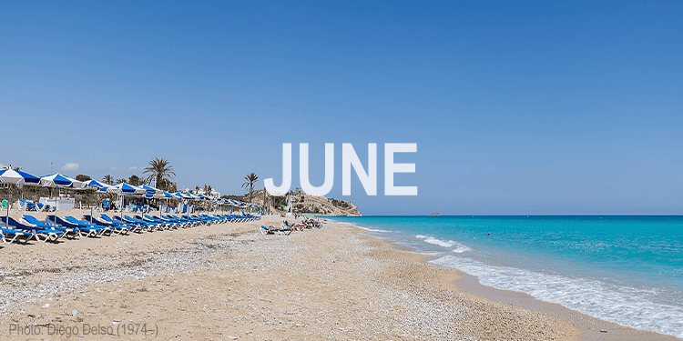 Beach scene with lounge chairs and umbrellas on a sunny day, representing summer in June.
