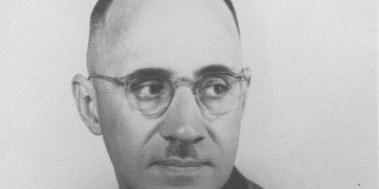 A man with glasses looking over his shoulder.