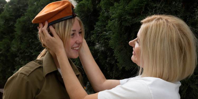 Woman embracing her child who is in uniform.