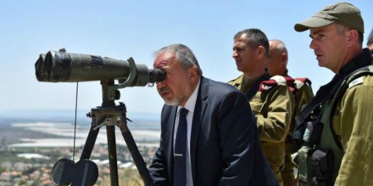 Man in a suit looking out a telescope with soldiers standing behind him.