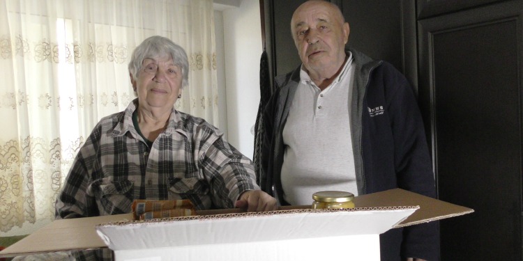 Lida and Nikolai, two Holocaust survivors standing next to an IFCJ branded food box.