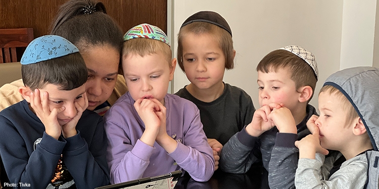 Little boys sitting around a table being read to