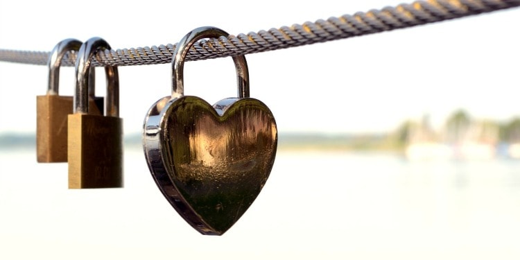 A heart lock and two regular locks hanging on a rope.