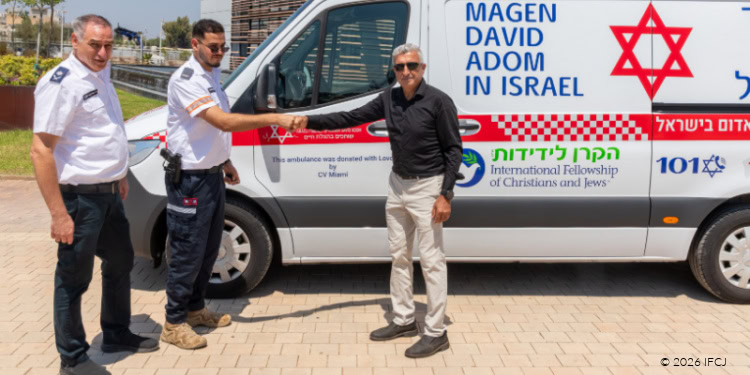 First responders and officials standing in front of a new ambulance donated to Israel, highlighting international aid and emergency preparedness.