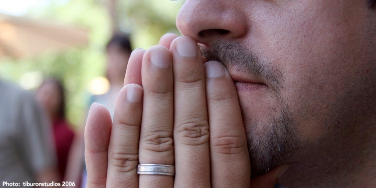 Man holding his hands up to mouth in a prayer position.