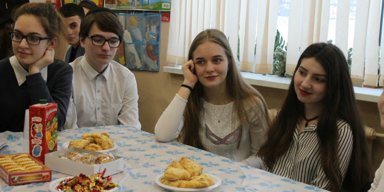Four young teens sitting together with treats sitting on the table in front of them.