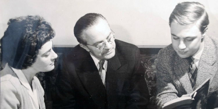 Black and white image of three people sitting together.