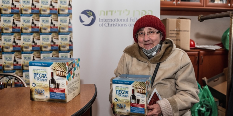 Elderly Jewish woman holding IFCJ matzah food delivery box.