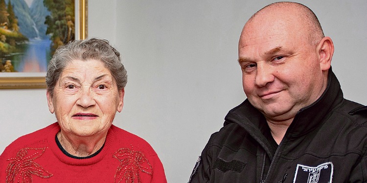 Elderly Jewish woman sitting next to a man while looking into the camera.